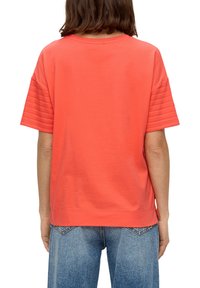 Koraalkleurig T-shirt van katoen met een losse pasvorm, korte mouwen en gestructureerde horizontale strepen op het schoudergedeelte, gecombineerd met blauwe jeans.