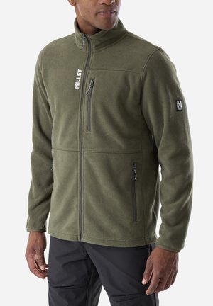 Mann trägt olivgrüne Fleecejacke mit vorderen und brustseitigen Reißverschlusstaschen, steht vor weißem Hintergrund.