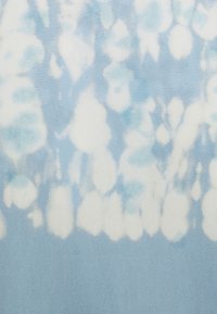 Světle modrá tkanina s vzorem batiky, která obsahuje různé odstíny modré a bílé kulaté tvary, vytvářející jemný, texturovaný vzhled.