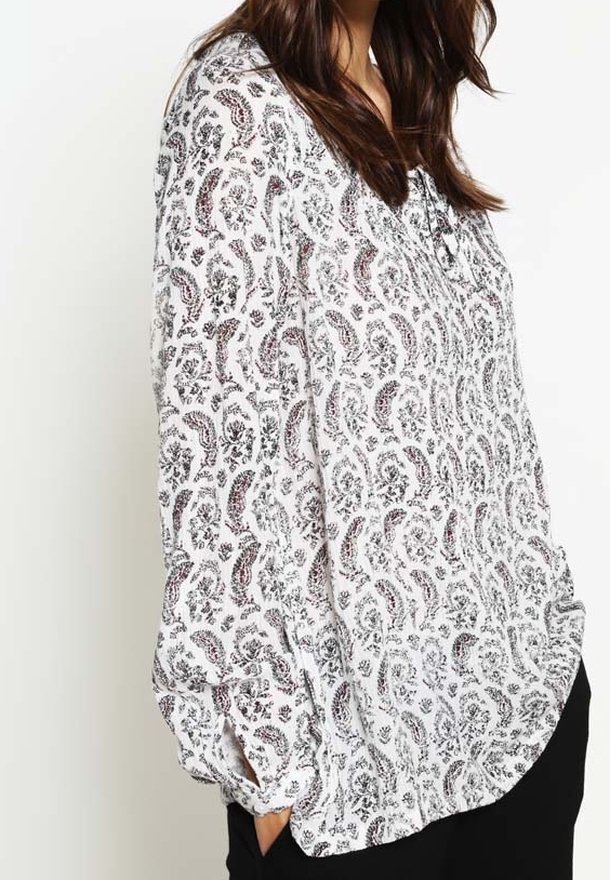 Blusa bianca a maniche lunghe con un motivo paisley nero e rosso, caratterizzata da una vestibilità rilassata, dettagli a bottoni e polsini arricciati.