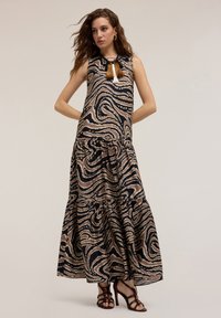 Rochie maxi dintr-un material fluid, cu un model spiralat în nuanțe de bej și negru. Are un design fără mâneci și un tiv cu volane. Accentuată cu ciucuri.