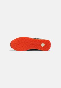 Sole di scarpa sportiva con un motivo testurizzato. Predominantemente in gomma arancione con un contorno nero. Presenta un accento quadrato vicino al tallone.