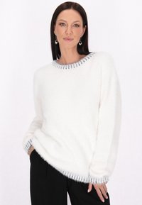 Pulover alb pufos cu guler și manșete gri cu nervuri. Prezintă o croială lejeră și umeri căzuți. Purtați peste pantaloni negri.