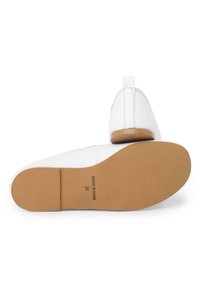 Zapatos de cuero blancos con un acabado suave, punta redondeada y un pequeño tacón tan. Forro interior suave y suela de goma texturizada.