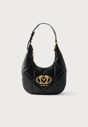 Μαύρη καπιτονέ τσάντα χειρός από συνθετικό δέρμα με καμπυλωτό σχήμα, λεπτομέρεια με χρυσό λογότυπο και έναν ρυθμιζόμενο ιμάντα. Κλείνει με φερμουάρ στην κορυφή.