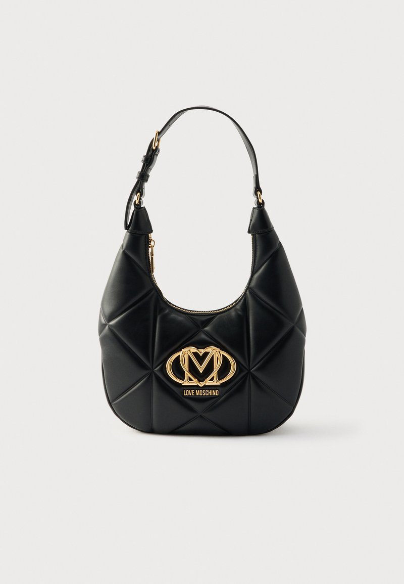 Μαύρη καπιτονέ τσάντα χειρός από συνθετικό δέρμα με καμπυλωτό σχήμα, λεπτομέρεια με χρυσό λογότυπο και έναν ρυθμιζόμενο ιμάντα. Κλείνει με φερμουάρ στην κορυφή.