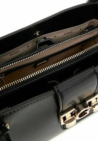 Sac à main en cuir noir avec une texture lisse, des accessoires en ton doré et plusieurs compartiments, y compris une section zippée.