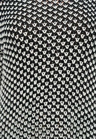 Πλεκτό ύφασμα σε ασπρόμαυρο με σχέδιο από μικρά, εναλλασσόμενα σχήματα V. Μαλακή υφή με διαφανή όψη.