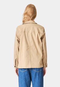 Tan bomuldsjakke med afslappet pasform, spids krave og lange ærmer. Har knapmanschetter og et enkelt rygdesign.