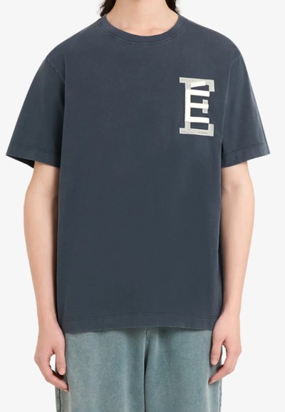 T-shirt à manches courtes gris foncé en coton, avec un logo brodé en argent texturé sur la poitrine gauche. Coupe droite.