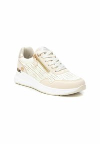 Zapatilla beige claro con diseño perforado, suela blanca y acentos metálicos. Incluye un cierre lateral y cordones texturizados.