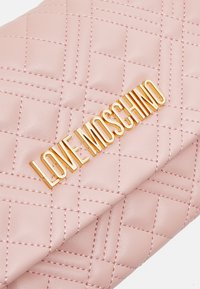 Pink quilted faux leather clutch featuring a gold "LOVE MOSCHINO" emblem, with contrasting stitching and a fold-over design.