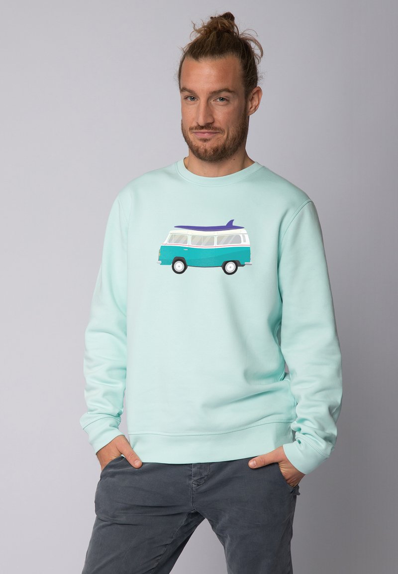 Sweatshirt vert menthe arborant un graphique d'un van de camping vintage avec une planche de surf sur le toit. Fabriqué dans un tissu doux avec des poignets côtelés.