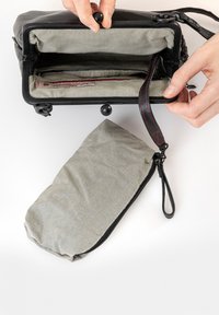 Borsa nera con interno a righe, dotata di una tasca con zip e una tracolla attaccata. Include una pochette abbinata a righe.
