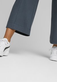 Blue textured cropped pants with a straight fit, paired with white sneakers featuring a black accent and thick soles.