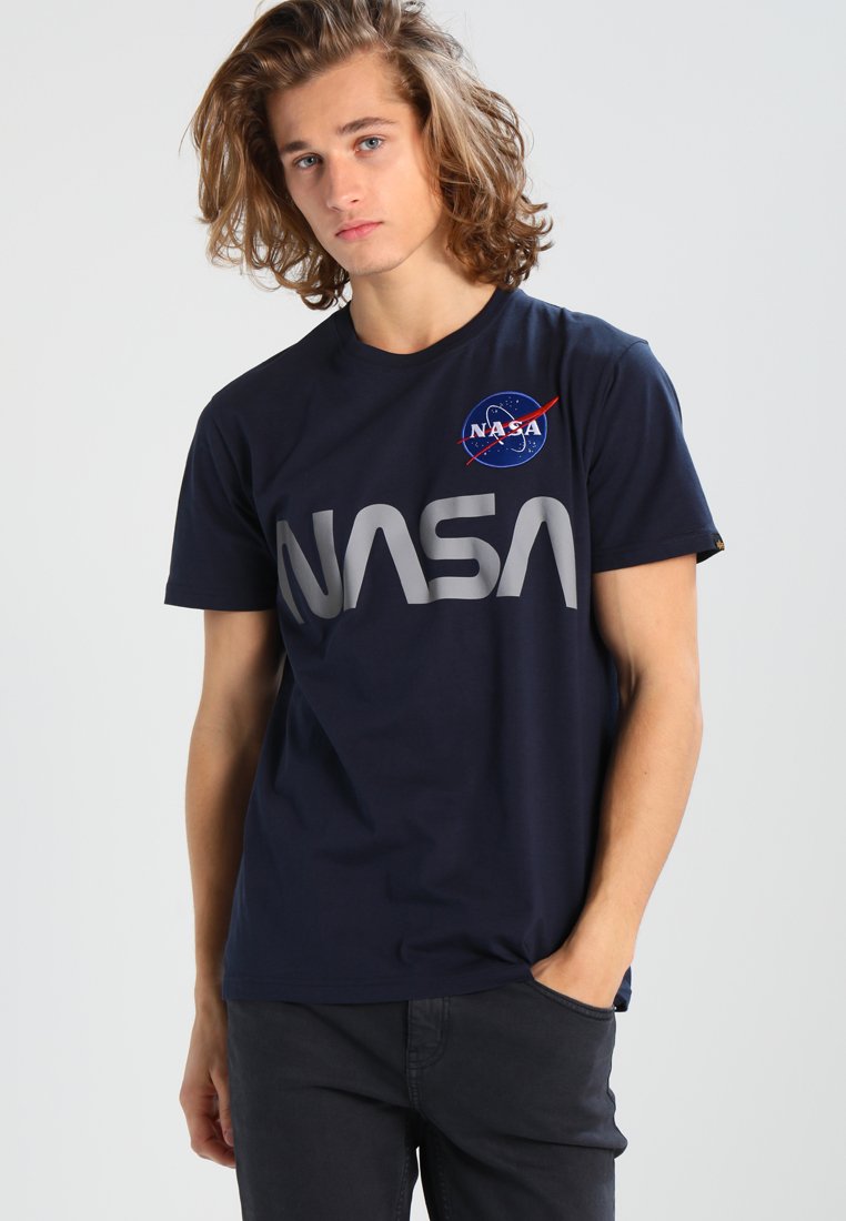 Camiseta de algodón azul marino con un gran logo gris de "NASA" y un parche circular de NASA en el pecho. Manga corta y cuello redondo.