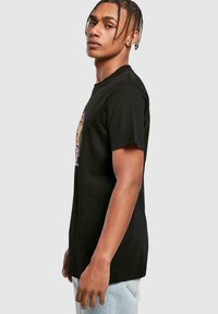 Sort bomulds T-shirt med et farverigt grafisk design på forsiden. Korte ærmer og en klassisk rund hals.