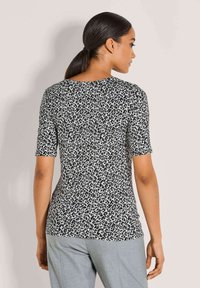 Kurzarmoberteil mit einem schwarz-weißen Leopardenmuster, Rundhalsausschnitt und taillierter Silhouette. Weicher, elastischer Stoff.