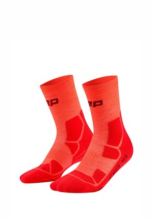 Pair of bright red athletic socks with darker red padded areas and black logo text on ankle and foot.