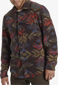 Fleece shirt met een geometrisch patroon in bruin, rood, blauw en groen. Voorzien van een knoopsluiting aan de voorkant en een borstzak. Zachte textuur.