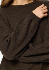 Maglione marrone lavorato a maglia con maniche ampie e scollo rotondo, che mostra una texture morbida e cuciture uniformi.