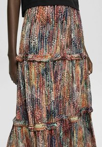 Jupe maxi avec un design superposé, ornée d'un motif abstrait multicolore vif et de volants à la taille et à l'ourlet. Tissu léger.