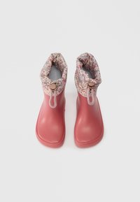 Ζευγάρι ροζ λάδι βροχής με φλοράλ υφασμάτινες μπαλόνες και ρυθμιζόμενα κορδόνια, προφίλ από πάνω σε λευκό φόντο.