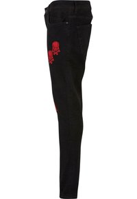 Melnas šaurās džinsās ar sarkanu kaulu un skeleta attēlu izšuvumu kreisajā augšstilbā. Izgatavotas no denima ar gludu tekstūru, paredzētas piegulošam izskatam.