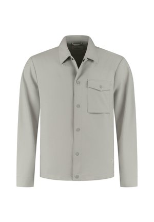 Camisa gris claro de manga larga con botonadura frontal, cuello puntiagudo y bolsillo en el pecho. Textura suave, diseño minimalista y sin patrones.