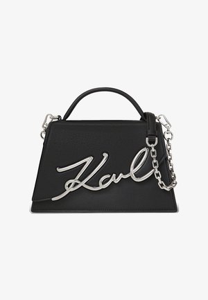 Melna ādas rokas soma ar strukturētu formu, izceļoties ar sudraba ķēdes siksnu un izteiktu kursīvas logotipa detaļu.