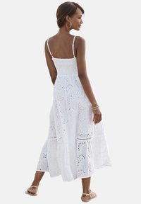Witte, mouwloze maxidress met een smocked lijfje, oogjes borduurwerk, een gelaagde rok en subtiele ruches aan de zoom.