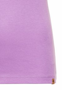 Lilla bomulds T-shirt med en glat tekstur, rund nederste kant og et lille logomærke i nederste højre hjørne. Enkel, tætsiddende design.