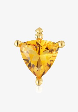 Gemme jaune facettée en triangle montée sur un sertissage en or avec des extrémités arrondies, photographiée sur un fond blanc.
