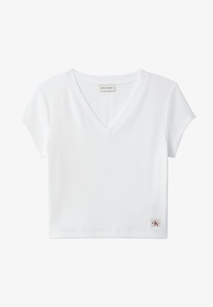 Top scurt alb, cu mâneci scurte, din material reiat, cu decolteu în V, cu etichetă Calvin Klein Jeans la gulerul din spate și cu mică emblemă CK pe tiv.