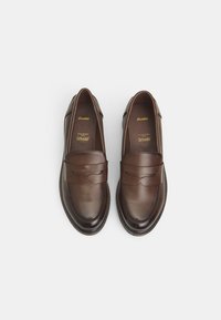 Smeđe kožne loafers cipele s glatkom završnom obradom, dekorativnim šavovima i uzdignutim naglaskom na sedlu. Jastučići za unutrašnjost označeni "Ortholite."