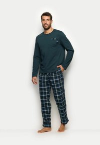 Pijama de hombre que incluye una parte superior de manga larga en verde oscuro con un bolsillo en el pecho y pantalones de cuadros azules. Los pantalones tienen una textura suave y una cinturilla elástica.