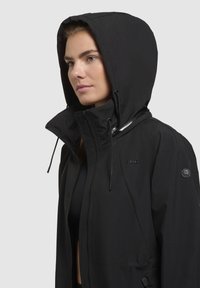 Giacca nera impermeabile con cappuccio, dotata di chiusura con zip, cordini regolabili e dettagli con logo sul petto e sulla manica.