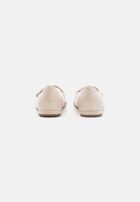 Ballerines en cuir verni beige clair, avec un bout rond, de subtils détails de couture et une semelle basse et lisse.