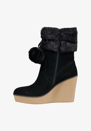Bottes compensées en suède noir avec un revers en fausse fourrure texturée, fermeture à glissière et un détail de pompon décoratif. Semelle compensée en beige clair.