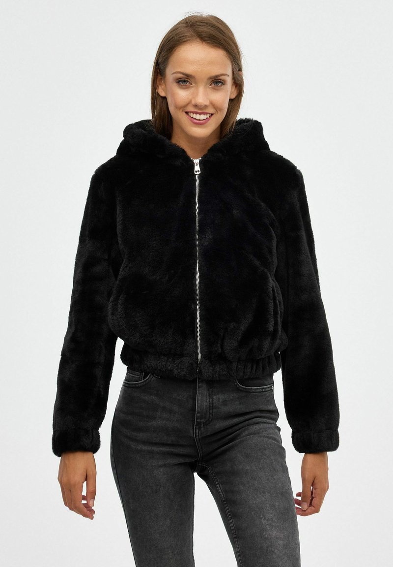 Chaqueta de pelaje sintético negro con cremallera y capucha, dobladillo y puños elásticos, que presenta una textura suave y herrajes plateados en contraste.