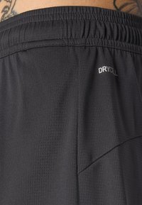 Pantalones cortos deportivos negros hechos de tejido transpirable con un acabado texturizado, que cuentan con una cinturilla elástica y una etiqueta "DRYCELL" en el lateral.