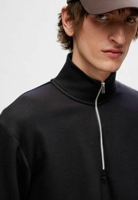 Zwarte zip-up kraag sweatshirt van een zachte stof, met een metalen rits en een hoge halslijn. Eenvoudig, modern ontwerp zonder zichtbare patronen.