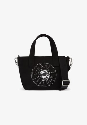 Μαύρη τσάντα tote με κοντά χερούλια και αποσπώμενο ιμάντα ώμου, με κουκκιδωτό κυκλικό λογότυπο που απεικονίζει στυλιζαρισμένο πρόσωπο με γυαλιά ηλίου.