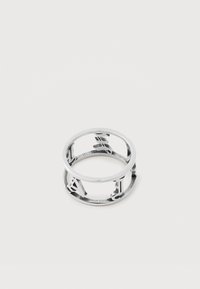 Ασημένιο μεταλλικό δαχτυλίδι με κομμένα γράμματα που σχηματίζουν κυκλικό σχέδιο σε απλό λευκό φόντο.