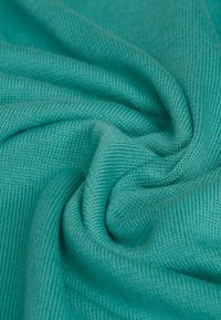 Türkisfarbener Strickstoff, weiche Textur, glatte Oberfläche, mit einem gerippten Muster, das eine spiralförmige Falte in der Mitte bildet.