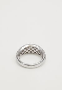 Bague en argent avec un motif en treillis à l'intérieur et de petits diamants incrustés le long des bords extérieurs sur un fond blanc.