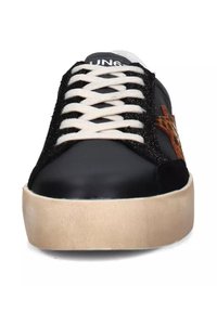 Basket noire avec des lacets blancs, une semelle beige douce et un panneau latéral noir texturé. Présente un accent à motif léopard sur le côté.