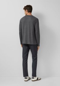 Gray sweater with a rounded neckline, long sleeves, and a relaxed fit, paired with dark pants and white sneakers with black accents.