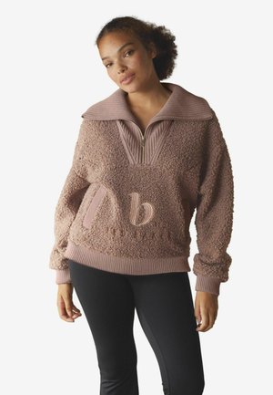 Fleece pullover sweatshirt in dusty rose with a ribbed collar, half-zip front, and a textured pattern; features an embroidered logo detail.