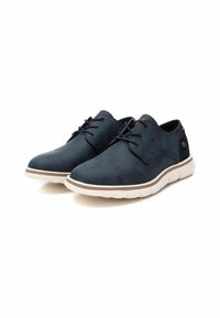 Zapatos casuales de color azul marino hechos de material sintético suave, con punta redonda, cordones en la parte delantera y una suela blanca texturizada.